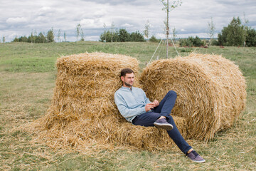 Naklejka na ściany i meble a man in a light shirt on sheaves of hay in the summer in a field
