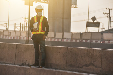 A man engineer holding a tablet at a road construction site