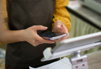 A smartphone in the hand of a coffee shop employee Check the amount that the customer paid online at the checkout counter.
