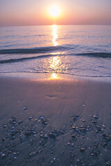 The sun rises on the sea coast. Calm water. Pink-lilac dawn. - 412922414