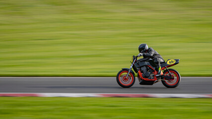 A panning shot of a racing motorbike as it circuits a track.