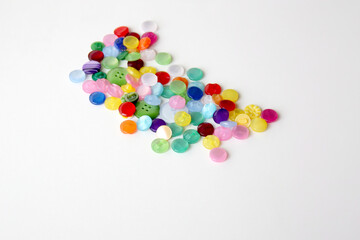 Multi-colored sewing buttons lie on a white background. Concept - sewing clothes. Horizontal photo. Selective focus.
