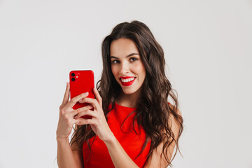 Naklejka premium Happy beautiful brunette girl smiling while using mobile phone