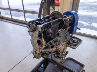 in the garage there is an opened engine block of a car