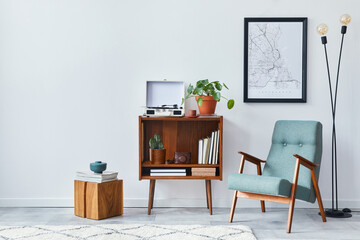 Modern retro composition of living room interior with design wooden cabinet, stylish armchair, mock up poster map, plants, vinyl recorder, books and personal accessories in home decor. Template.