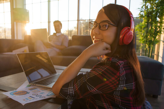 Caucasian man and Asian woman couple working at home in orange sunlight of evening twilight time with beautiful warm sun light. Idea for happiness and sharing good time for modern businesspeople