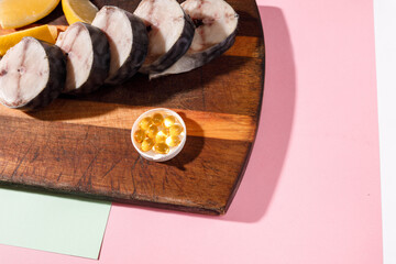 Fresh chopped mackerel lies on a kitchen board along with cod-liver oil capsules