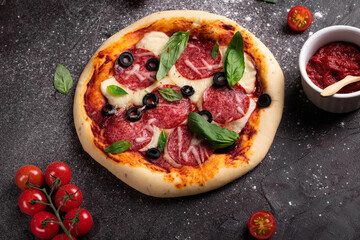 Flat lay of freshly baked pizza with olives and basil on a black background