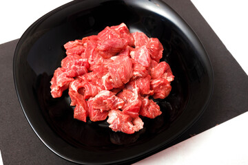 pork chopped into small pieces in a black plate on a bright colored background