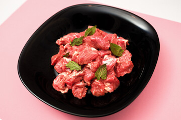 pork chopped into small pieces in a black plate on a bright colored background