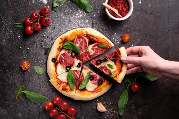 Hands holding a piese of freshly baked pizza