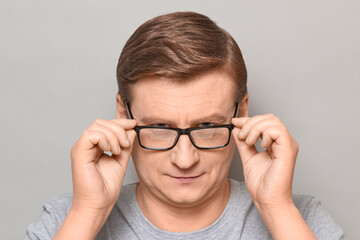 Fototapeta premium Portrait of blond mature man looking attentively over his glasses