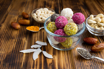 Closeup on diferents energy balls in the glass bowl and ingredients on the wooden surface