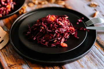 Red cabbage salad (coleslaw) with apples, oranges and walnuts on a dark wooden background, food still life