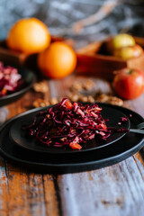 Red cabbage salad (coleslaw) with apples, oranges and walnuts on a dark wooden background, food still life