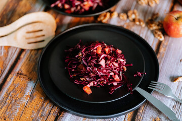 Red cabbage salad (coleslaw) with apples, oranges and walnuts on a dark wooden background, food still life