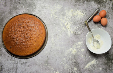 On a stone base and zenith view. Homemade sponge cake, part of the ingredients and utensils. 