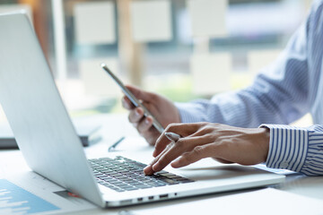 Close up Business man using calculator and laptop for do math finance on wooden desk, tax, accounting, statistics and analytical research concept