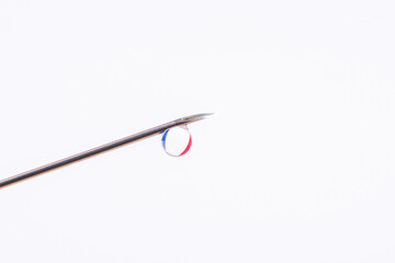 Vaccination in France. Needle with a small drop against flag of France in the background. Photo with copy space