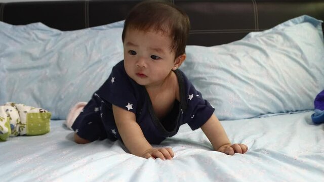 portrait of 8 month Asian Chinese baby boy looks and move around surprisely on a bed