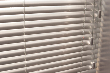 Aluminum blinds on the office windows. Made from metal. Venetian blinds closeup on the window. Silver color. Closed horizontal blinds in sunny day. Modern sun protection and window decoration.