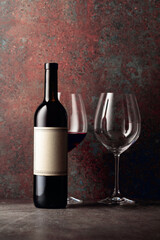 Bottle of red wine with old empty label on rusty brown background.