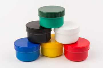 Closed plastic jars with paint of different colors for children's creativity on white background....