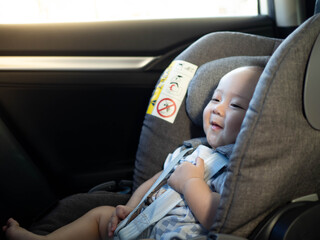Baby child fastened with security belt in safety car seat.