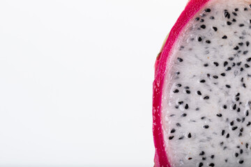 Ripe dragon fruit or pitaya cut in half with seeds visible on white background