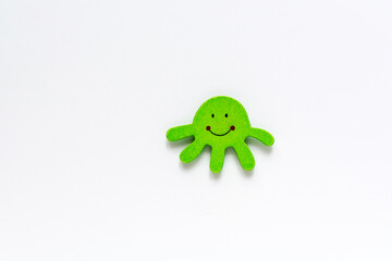 Organic baby green octopus isolated on white background with copy space. Baby fun wooden toy and teether on pink background. Top view, flat lay. Wooden animal miniature toys set mockup for babies.