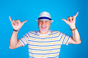 Senior male on blue background positive having fun gesturing feeling younger