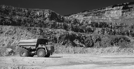 Mining dump truck in limestone quarry, black and white panorama.