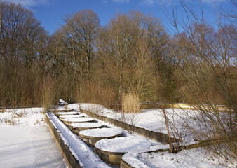 Water basins of an abandoned and decayed outdoor swimming pool in wintertime with snow