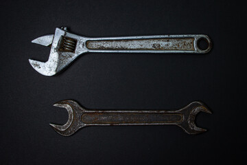 Wrench and adjustable wrench on a black background. Old working tools. Steel tools