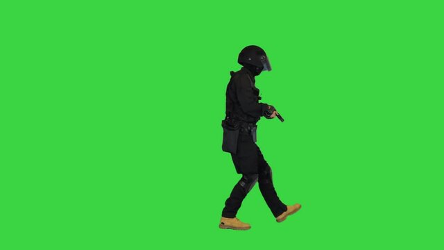 Police SWAT armed fighter walking with a hand gun on a Green Screen, Chroma Key.