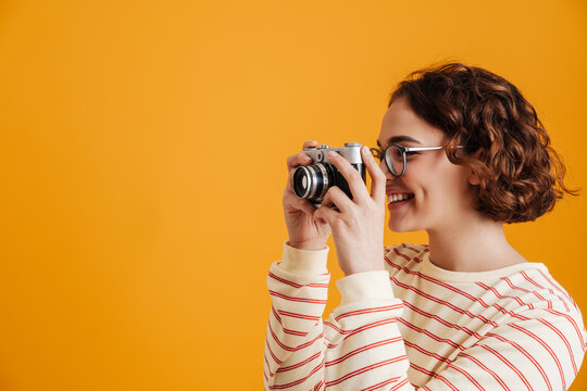 Cheerful young woman taking photos with camera