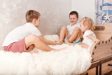 three cheerful children play on the bed. children tickle each other bare feet at home