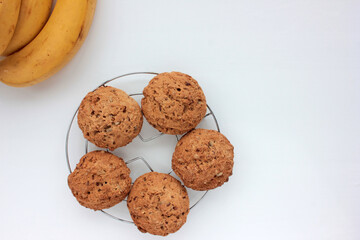 Oatmeal banana cookies on white table. Overhead view of oat biscuits and yellow fruits on white background with copy space