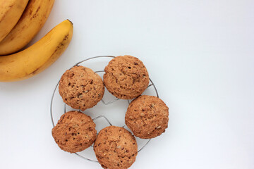 Oatmeal banana cookies on white table. Overhead view of oat biscuits and yellow fruits on white background with copy space
