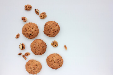 Homemade oatmeal cookies with walnuts on white table. Overhead view of oat biscuits and nuts on white background with copy space