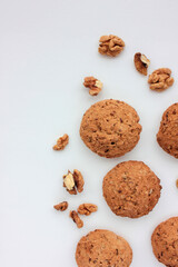 Homemade oatmeal cookies with walnuts on white table. Overhead view of oat biscuits and nuts on white background with copy space
