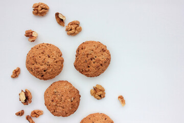 Homemade oatmeal cookies with walnuts on white table. Overhead view of oat biscuits and nuts on white background with copy space
