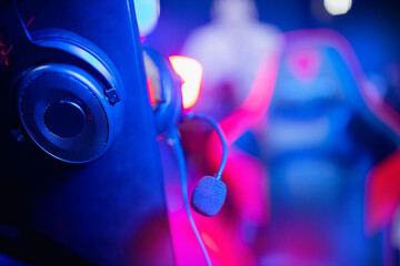 Headphones with microphone for video games and cyber sports on neon background of gaming monitor
