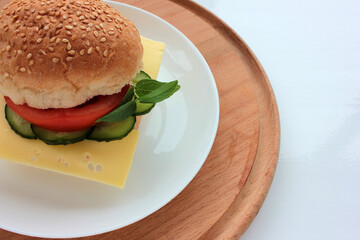 Cheese burger with tomato, cucumber and greens on white background. Healthy fast food. Sandwich with fresh vegetables.