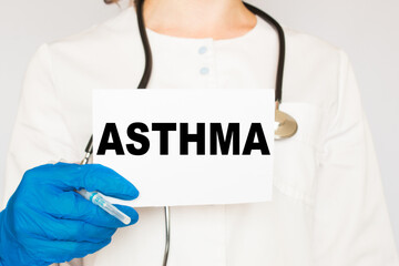 The doctor's blue - gloved hands show the word ASTHMA - . a gloved hand on a white background. Medical concept. the medicine