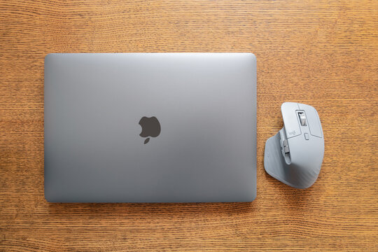 Apple macbook laptop closed with wireless mouse on wooden background.. Communication network. Silver metal surface. Digital modern communication. Computer technology. 04.02.2021 Almaty, Kazakhstan.
