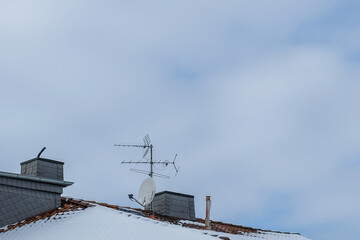 old TV or television antennas on a snow-covered roof