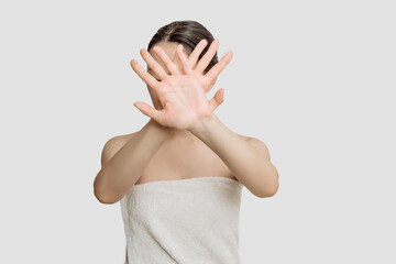 a young woman in a towel after spa treatments shows a sign of refusal, protest, stop.