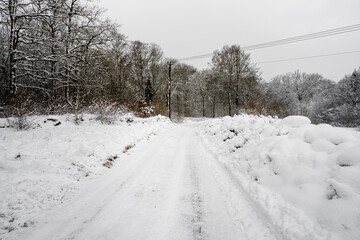 Obraz premium An icy and snowy winter road going through a meadow and forest landscape. Picture from Scania, southern Sweden