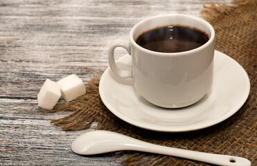 Coffee cup with sugar and spoon on a black wooden background. Coffee is an invigorating and tonic...